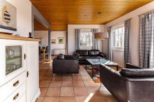 a living room with leather furniture and a wooden ceiling at Ferienhuus Wietkieker in Nordstrand
