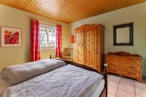 a bedroom with a bed and a dresser and a window at Ferienhuus Wietkieker in Nordstrand +15 photos