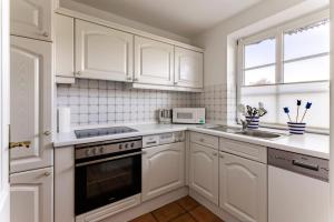 a white kitchen with white cabinets and a sink at Friesenhof am Deich in Nordstrand