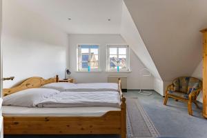a bedroom with a bed and a window and a chair at Friesenhof am Deich in Nordstrand +11 photos