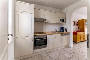 a kitchen with white cabinets and a stove top oven at Haus am Kurhaus 9 in Nordstrand