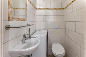 a white bathroom with a sink and a toilet at Haus am Kurhaus 9 in Nordstrand +8 photos