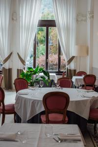 a restaurant with white tables and chairs and windows at Hotel Bigio in San Pellegrino Terme