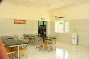 a dining room with tables and chairs and a window at Skandavanam in Tiruvallūr