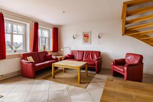 a living room with red couches and a table at Haus im Halligweg 18 in Nordstrand