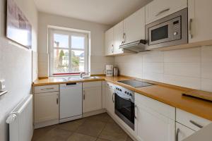 a kitchen with white cabinets and a sink and a microwave at Haus im Halligweg 18 in Nordstrand +14 photos