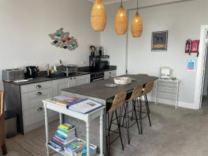 a kitchen with a counter with stools and a table at Sunrise Apartment in Weymouth +14 photos