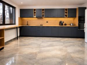 a kitchen with black cabinets and a tile floor at Hillcrest Panorama Valea Prahovei in Poiana Comarnic