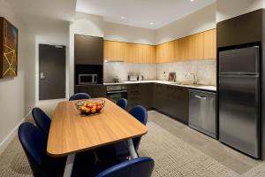 
a kitchen with a table and chairs and a refrigerator at Quest Port Adelaide in Adelaide
