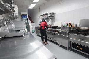 a person standing in a kitchen preparing food at Zoé’s Paradise Waterfront Hotel in Tuktuk Siadong