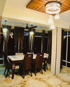 a dining room with a table and chairs and windows at Pine Tree Resort Betla in Kechki
