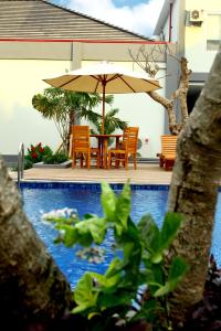 a table with an umbrella next to a swimming pool at Grand Royal BIL Hotel in Praya