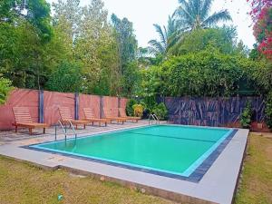 a swimming pool with two benches around it at BTI Leisure Hotel in Kataragama +11 photos