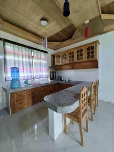 a kitchen with wooden cabinets and a table and chairs at The Red Roof in Batuan
