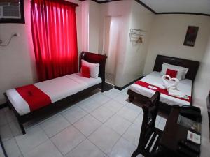 a bedroom with two beds and a red curtain at RedDoorz near Ormoc Port Terminal in Ormoc