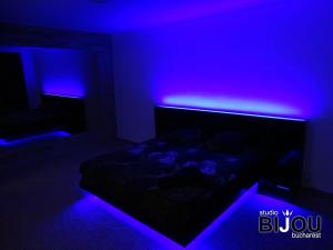 a dark room with a bed with purple lights at Studio Bijou Bucharest in Bucharest