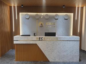 a reception desk in a building with clocks on the wall at Hotel Srs Manor in Hārohalli