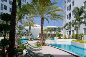 an image of a resort swimming pool with palm trees at Stylish Pool View 1BDR Apartment Bang Tao in Ban Thalat Choeng Thale