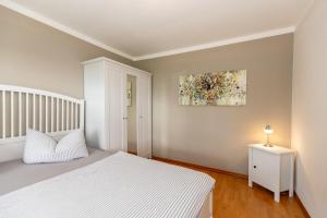 a bedroom with a white bed and a painting on the wall at Bungalow Becker "Am Feldrand" in Jennewitz