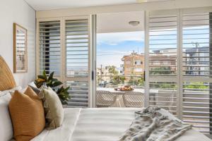 a bedroom with a bed and a balcony with a view at Salt & Sky - Stylish Apartment with Pool & Spa in Caloundra