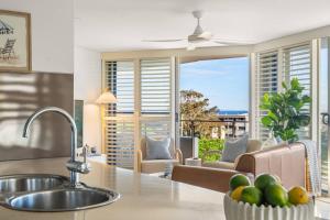 a kitchen and living room with a view of the ocean at Salt & Sky - Stylish Apartment with Pool & Spa in Caloundra