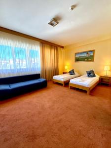 a hotel room with two beds and a couch at Hotel - Restaurant Gonduzo in Odorheiu Secuiesc +43 photos