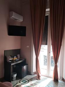 a living room with a window with curtains and a television at Affittacamere Stella Rooms in Reggio di Calabria