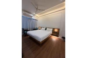 a bedroom with a white bed and wooden floors at The Shivanta Inn in Ābu Road