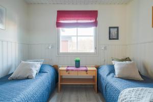 two beds in a room with a table and a window at Järven Helmi in Äkäslompolo