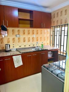 a kitchen with wooden cabinets and a sink and a dishwasher at The John Apartment in Murtala Muhammed International Airport