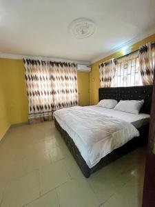 a bedroom with a large bed with white sheets at The John Apartment in Murtala Muhammed International Airport