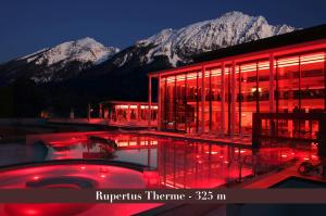 a building with a swimming pool in front of a mountain at Villa Dora Petit Hôtel in Bad Reichenhall