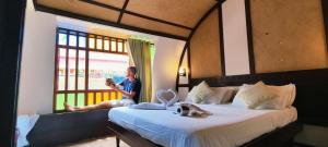 a man sitting on a bed looking out a window at Traditional Houseboat in Alleppey