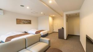 ein Hotelzimmer mit zwei Betten und einer Couch in der Unterkunft HOTEL nehako in Hakone