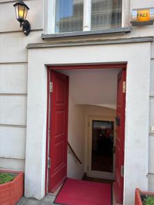 eine rote Tür eines Gebäudes mit einem roten Teppich in der Unterkunft Hotel Amelie Berlin in Berlin