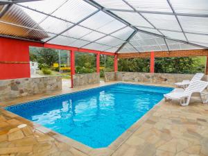 a swimming pool with a roof over it with two chairs at Pousada Monjolos de Minas a 9 km de Gonçalves in Gonçalves