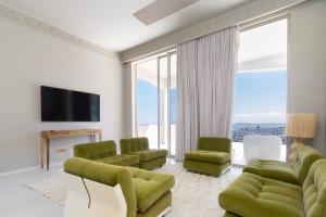 a living room with green chairs and a television at Luxury 8-Suite Villa with Heated Pools, Ocean & Mountain Views in Cape Town
