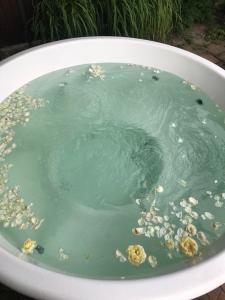 a bath tub filled with green water with bubbles at Villa del Grossa Будинок з каміном та чаном на дровах in Kuchakiv +26 photos