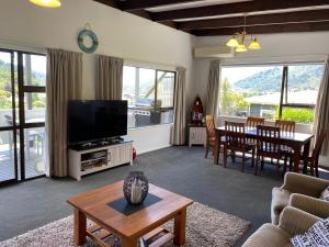 a living room with a flat screen tv and a table at Harbour View on Buller in Picton