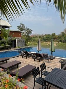 a deck with tables and umbrellas next to a swimming pool at Namkhan Rivora Resort in Luang Prabang