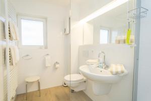 a white bathroom with a toilet and a sink at Weststrand, App 11 "Seewind" in Westerland