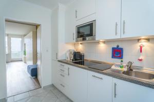 a kitchen with white cabinets and a sink at Weststrand, App 11 "Seewind" in Westerland