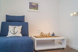 a bedroom with a blue chair and a table at Weststrand, App 11 "Seewind" in Westerland