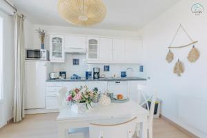 a white kitchen with a table with flowers on it at 11- Clapotis de l'Ô - Balcon sur la Mer - Parking Privé in Ault