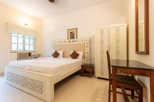 a bedroom with a white bed and a desk and a table at AV apartment beach candolim in Aguada +39 photos