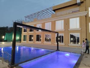 a man and a child standing next to a swimming pool at La Fenice Resort Madh Island in Mumbai