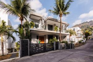 a white house with palm trees in front of it at Villa Momo seaview pool & game room Kata in Kata Beach