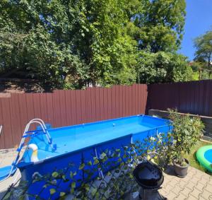 a blue swimming pool in a yard with a fence at Pensiunea NikoBella Panzió in Sovata
