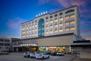 a large building with cars parked in a parking lot at 花祺巨幕影院酒店 儋州那大镇夏日广场汽车站店 in Danzhou