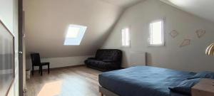 a bedroom with a bed and a chair and windows at Logement 2 - proche Le Mans in Aigné +3 photos